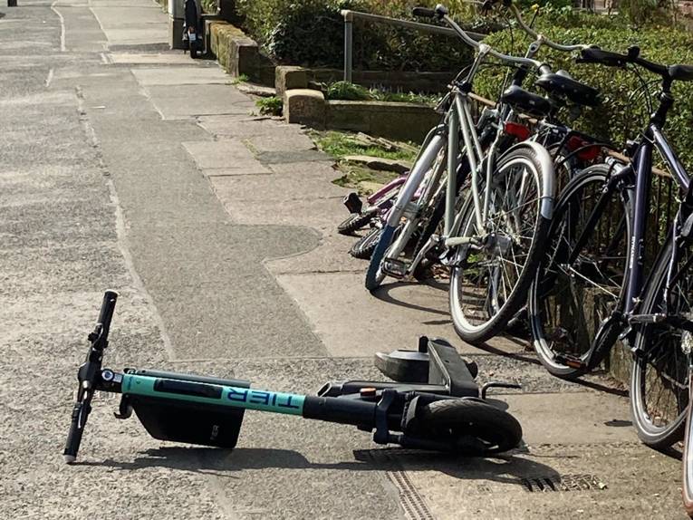 Ein Elektro-Roller liegt auf dem Bürgersteig